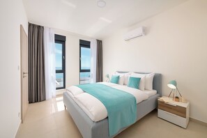 Ein modernes Schlafzimmer mit Bett, Nachttisch und Blick zum Himmel.