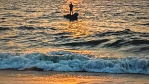 Ein Sonnenuntergang über dem Meer mit einer Person auf einem Stand-Up-Paddleboard.