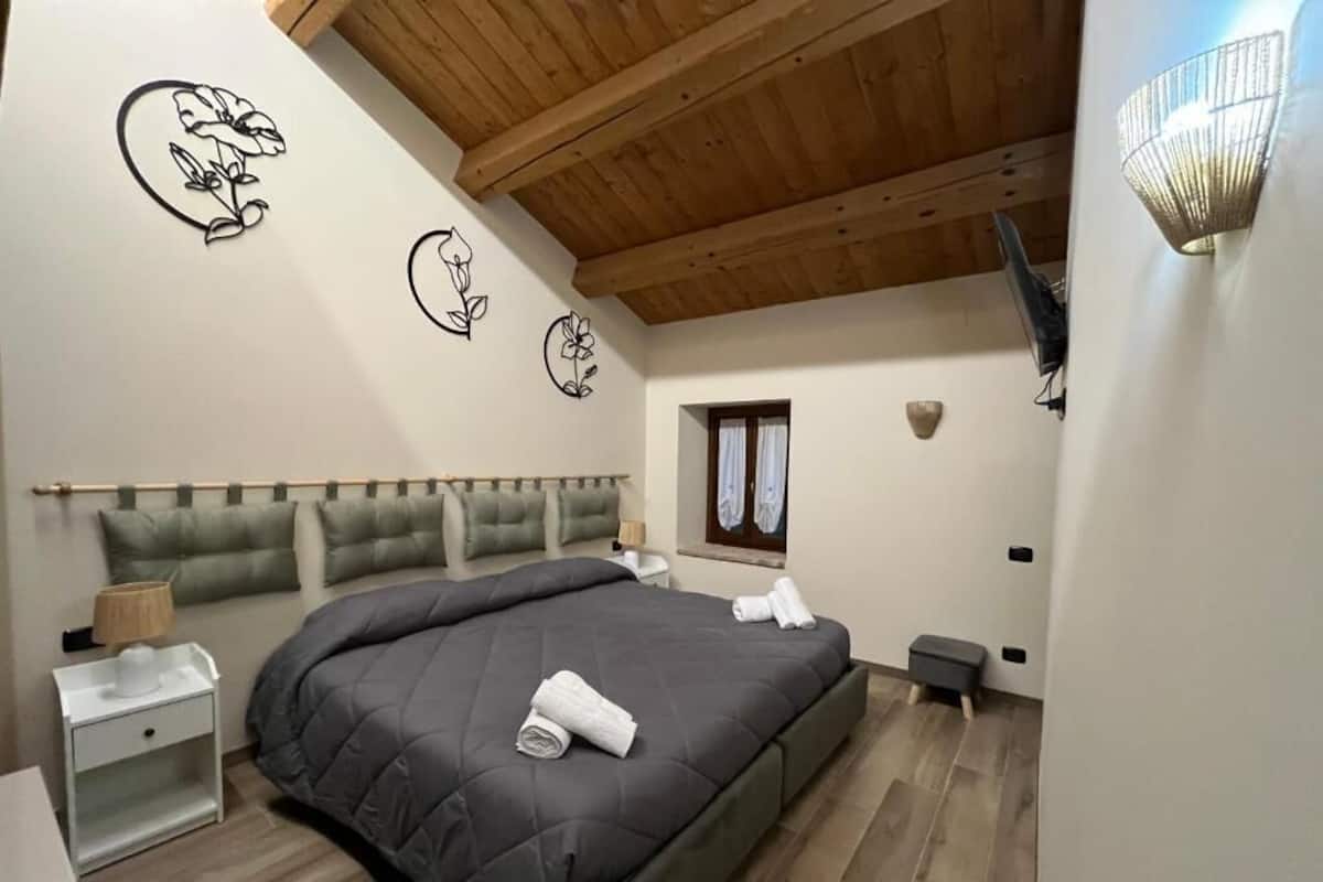 A bedroom with a large bed, a nightstand, a lamp, and wall art.