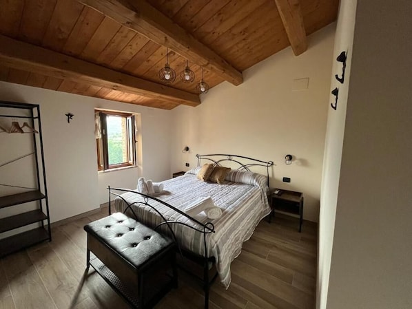 A bedroom with a bed, a bench, a window, and a wooden ceiling. - Sibilroom - Rooms & Wellness (Amandola)
