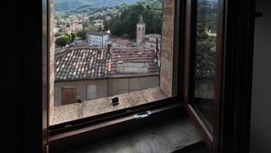 A window with a view of a town, including buildings and a tower. - Sibilroom - Rooms & Wellness (Amandola)