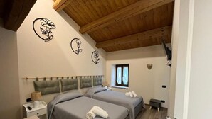 A bedroom with two beds, a wooden ceiling, a window, and a nightstand with a lamp. - Sibilroom - Rooms & Wellness (Amandola)