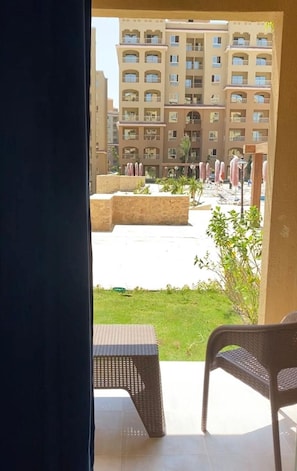 An outdoor seating area with a view of a multi-story building. -   شاليه عائلي فاخر  بجاردن في AquaView – أكوافيو (elhammam)