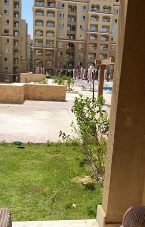 A hotel courtyard with a pool, lounge chairs, and a view of high-rise buildings. -   شاليه عائلي فاخر  بجاردن في AquaView – أكوافيو (elhammam)