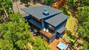Una casa moderna de dos pisos con terraza, mobiliario exterior y un jacuzzi.