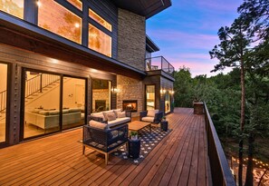 Ein modernes Haus mit einer Terrasse, einem Kamin und einer Treppe, die zu dem oberen Stockwerk führt.