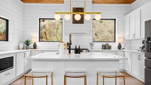 Una cocina moderna con una isla grande, armarios blancos y techo de madera.