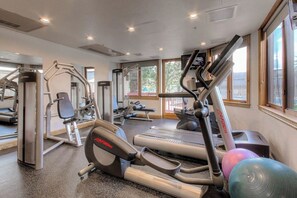 Un gimnasio con cintas de correr, elípticas y equipo de pesas.