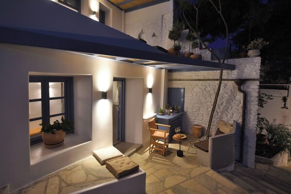 Eine Terrasse mit Steinboden, einem Stuhl, einem kleinen Tisch und einem Blumentopf.