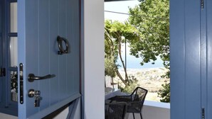 Una habitación con una puerta azul que da a una zona de estar al aire libre con vista al mar.