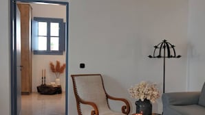 Una habitación con una mesa de centro de madera, una silla, una lámpara de pie y un acceso a otra habitación.