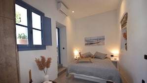 Un dormitorio con cama, mesitas de noche, una ventana y un cuadro en la pared.