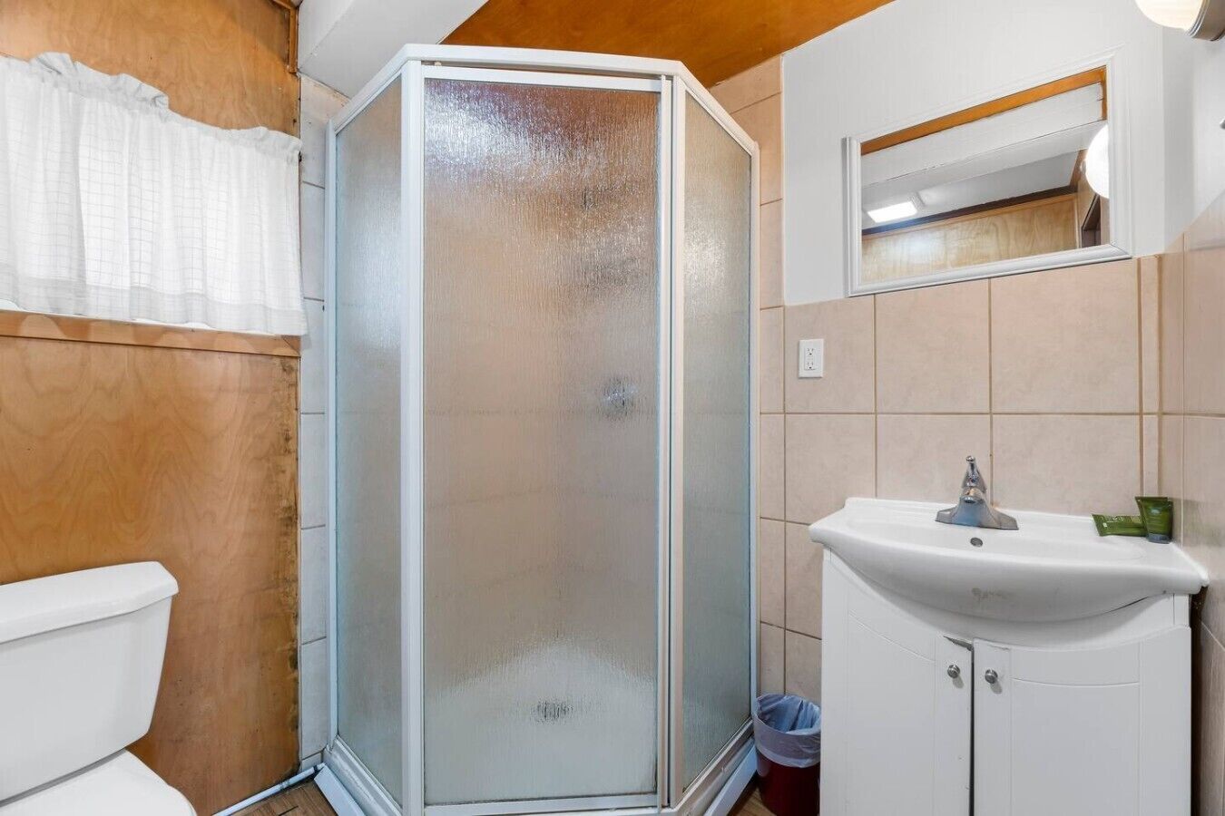A bathroom with a glass-enclosed shower, a white sink, and a mirror above the sink.