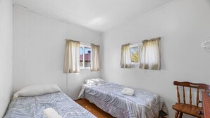 A room with two single beds, a wooden chair, and a window with curtains. - Relaxing Countryside Stay (Bailieboro)