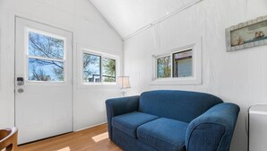 Ein Zimmer mit einem blauen Sofa, zwei weißen Türen, einer Lampe und einem kleinen Bilderrahmen an der Wand.
