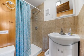 Ein Badezimmer mit Dusche, Toilette, Waschbecken und einem Spiegel über dem Waschbecken.