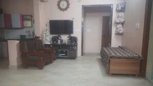 Una sala de estar con sofá, televisor y alfombra estampada.