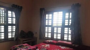 Un dormitorio con cama, mesita de noche y ventana con cortinas.