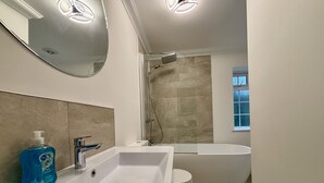 Un bany modern amb un lavabo, vàter i banyera de color blanc.