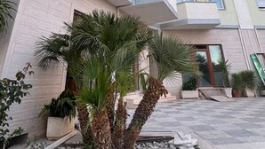 Ein mehrstöckiges Gebäude mit Balkonen, einem Innenhof mit Palmen und einem Schachbrettmuster auf dem Boden.