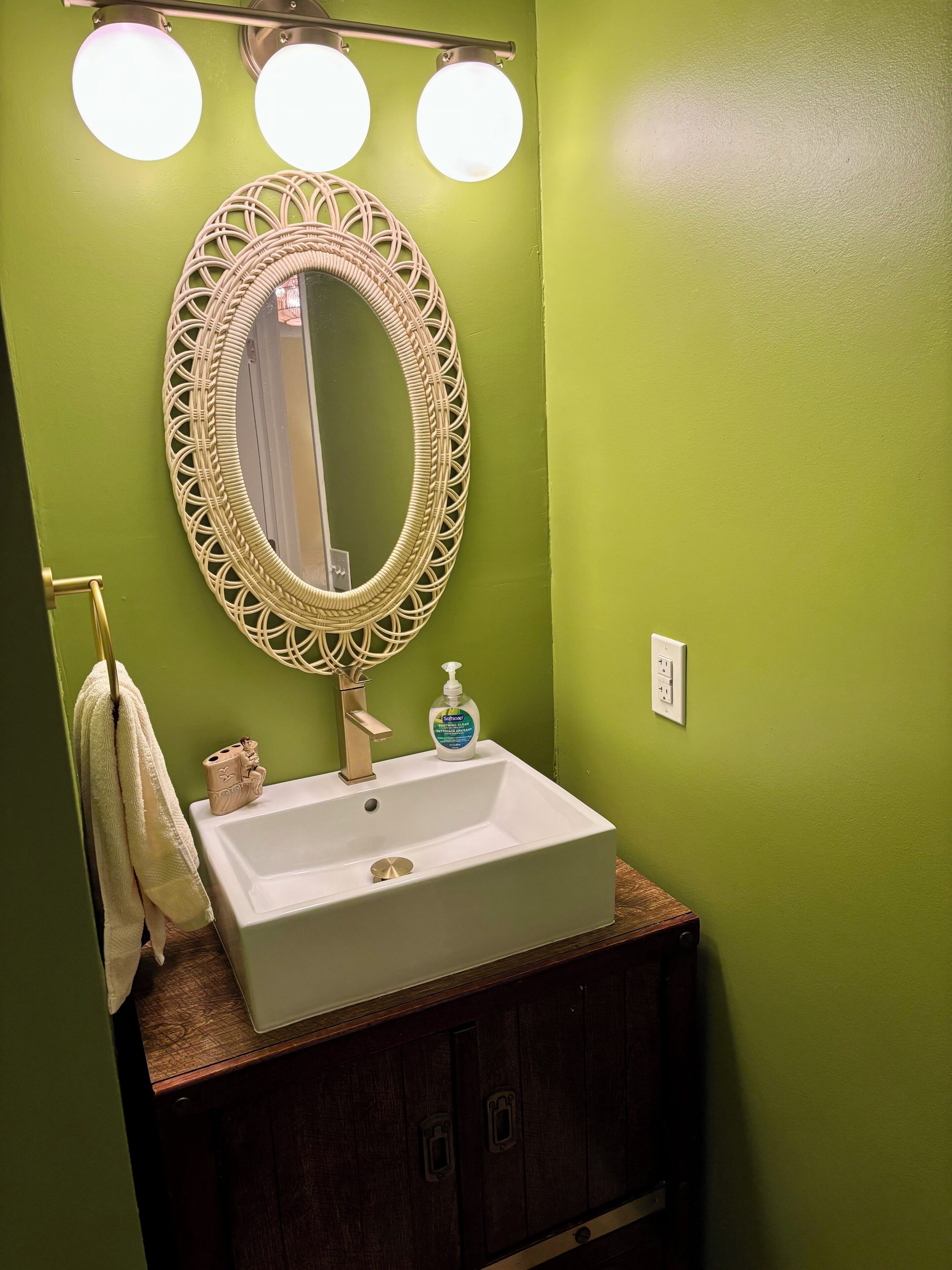 A bathroom with a white sink, a decorative mirror, and a towel rack.