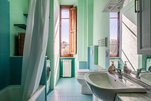 Un bagno con vasca, servizi igienici, lavandino e finestra con vista esterna.