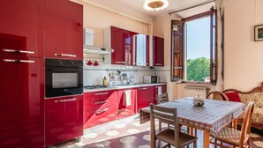 Una cucina compatta con mobili rossi, un tavolo da pranzo con sedie e una finestra vista.