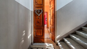 Un corridoio con una porta in legno, una decorazione a forma di cuore e una scala.