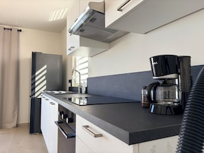 Eine moderne Küche mit Einbauherd, einer Kaffeemaschine und einem Kühlschrank.