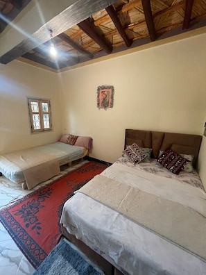 Une chambre avec deux lits, une fenĂȘtre, un Ă©lĂ©ment dĂ©coratif mural et un plafond en bois.