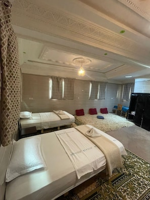 A hotel room with two beds, a massage area, and a TV.