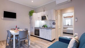 Ett kompakt bostadsutrymme med ett litet kök, en matplats och en soffa.