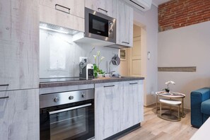 A modern kitchen with a built-in microwave, oven, and a small round table with a plant. - Civette A, Studio Apt with Shared Garden View (Greve in Chianti)