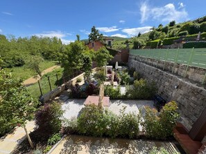 A courtyard with a stone wall, a tennis court, and lush greenery. - Civette A, Studio Apt with Shared Garden View (Greve in Chianti)