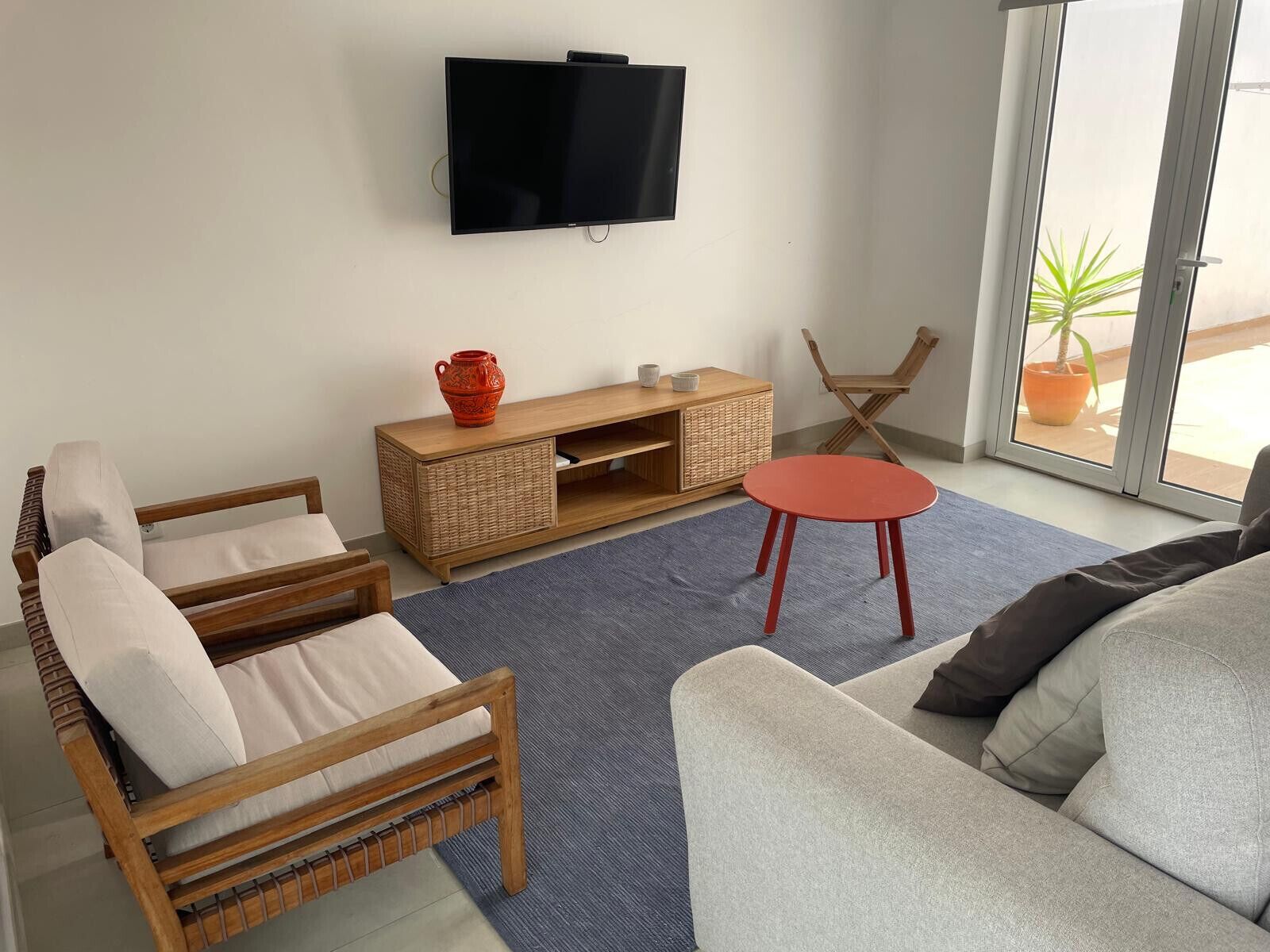 A living room with a TV, wicker console, and seating.