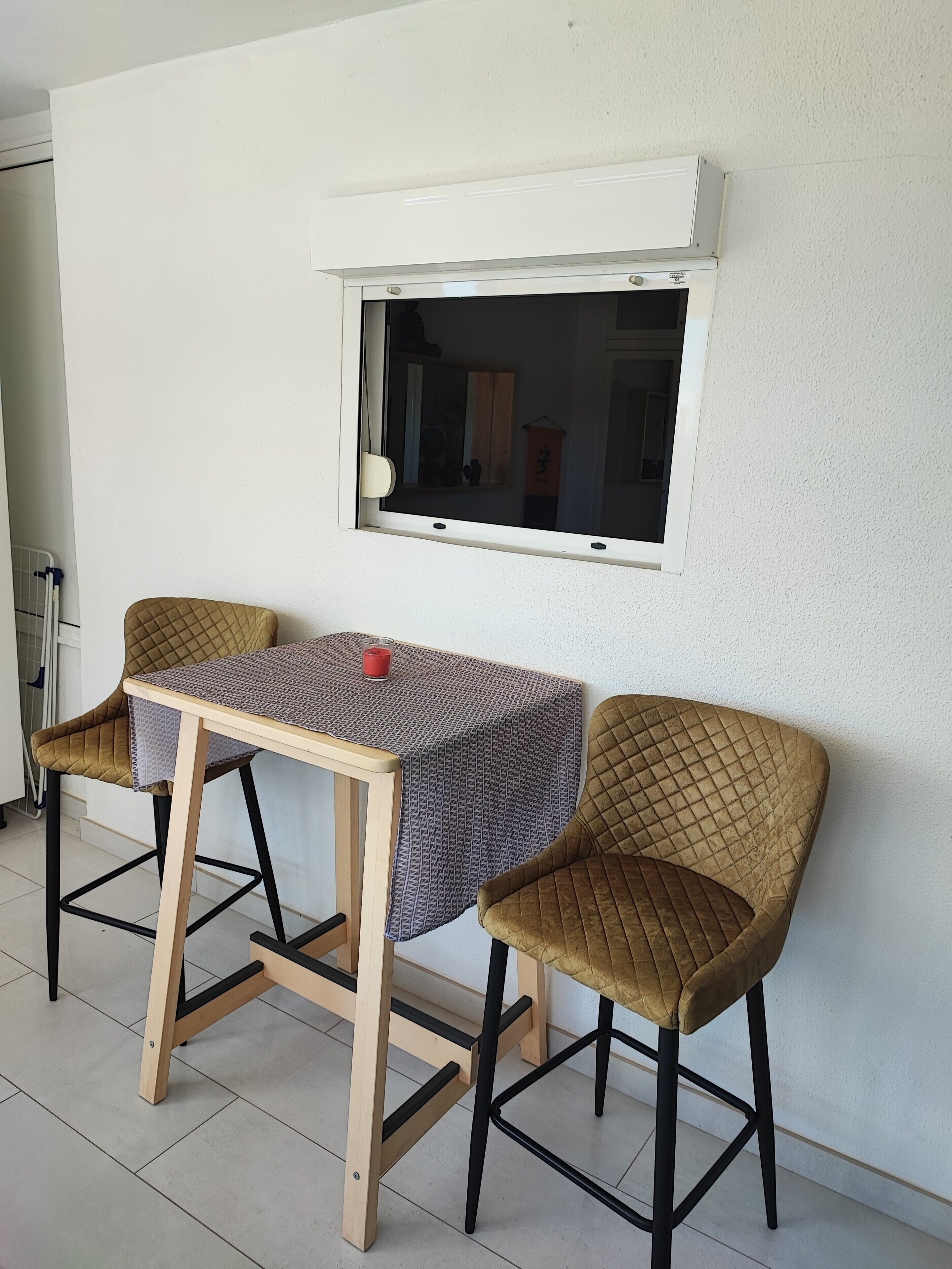 A small dining area with a table and two chairs, a window, and a radiator.