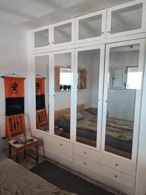 Une chambre à coucher comprenant un lit, une chaise, une armoire avec des portes miroir et une petite table.