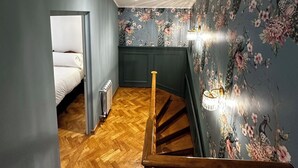 Eine Treppe mit Holzgeländer führt zu einem Schlafzimmer mit einem Bett.