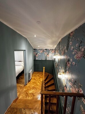 Eine Treppe mit Holzgeländer führt zu einem Schlafzimmer mit einem Bett.