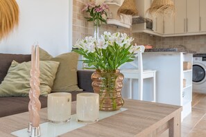 Ein Wohnzimmer mit Holztisch, Blumen in einer Vase und einem Sofa.