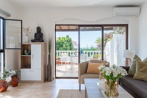 Ein Wohnzimmer mit einer Couch, einem Couchtisch und Blick ins Freie.