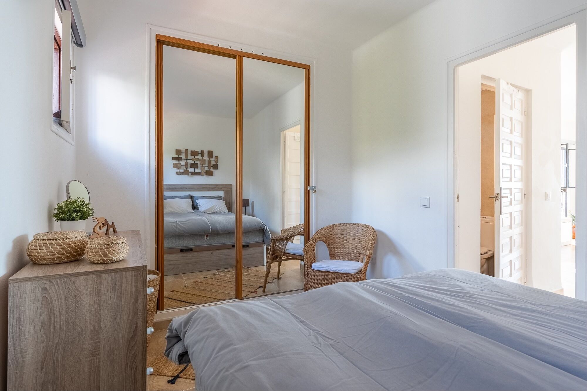 Un dormitorio con cama, armario, silla y una mesita con una planta.