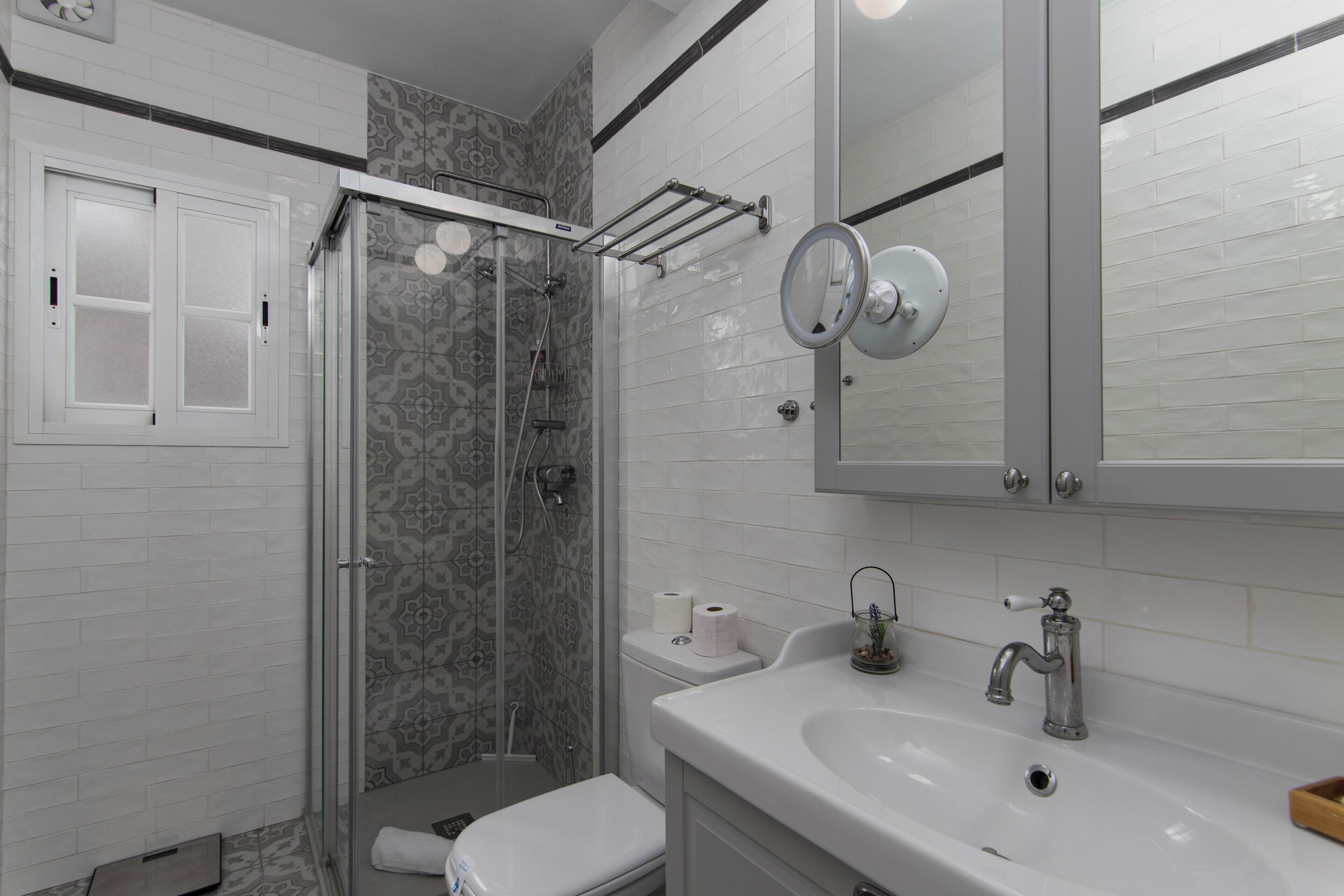 A bathroom with a shower, toilet, sink, and mirror.