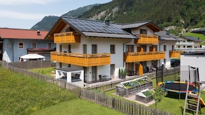 A two-story building with balconies, a garden, and a view of the mountains. - Apartment 'Gästehaus Egger 1' with Mountain View, Balcony and Wi-Fi (Grossarl)