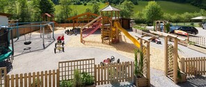 Un parque infantil con tobogán, columpios y una estructura para escalar.