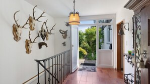 Een hal met een trap, een kroonluchter en dierlijke schedels aan de muur.