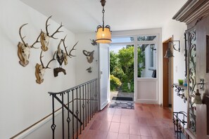 A hallway with a staircase, a chandelier, and wall-mounted animal skulls. - Holiday Home 'Leni' with Shared Terrace and Garden (Edertal)