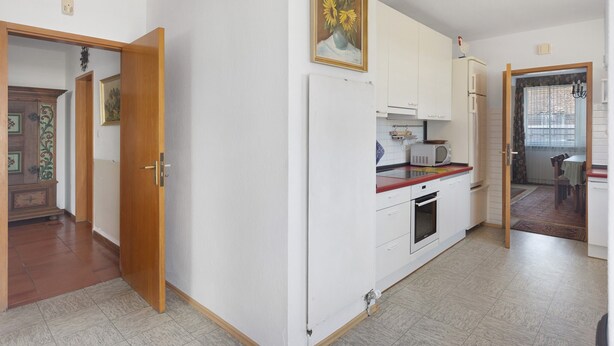 Una cucina con mobili bianchi, un forno a microonde e un piano di lavoro rosso.