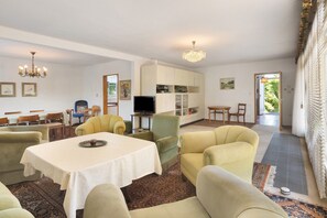 Ein Wohnzimmer mit Esstisch, Sofas, Fernseher und Küchenzeile.