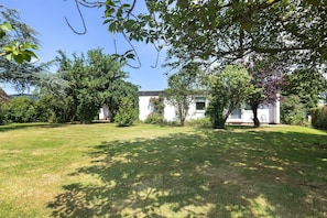 A residential property with a well-maintained lawn, a white house, and surrounding greenery.